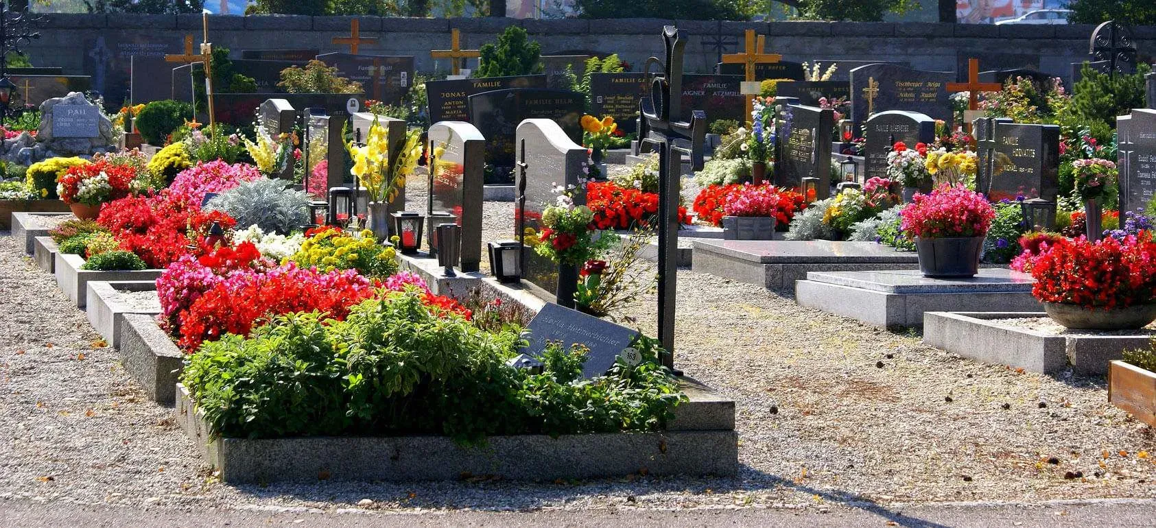 Tombes de cimetière ornées de nombreuses compositions florales colorées.