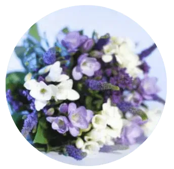 Bouquet rond d'hommage composé de fleurs blanches et violettes.